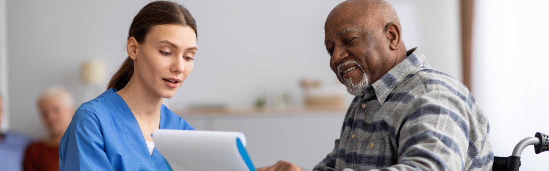 caregiver and senior man looking at the clipboard