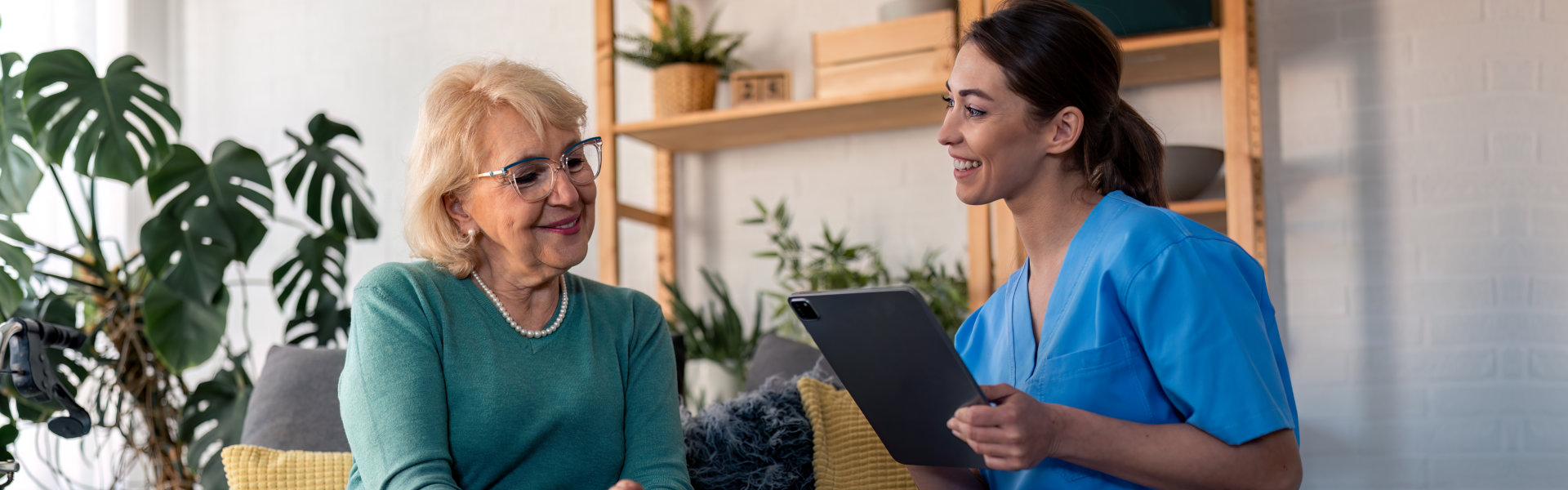 caregiver holding a tablet and senior woman