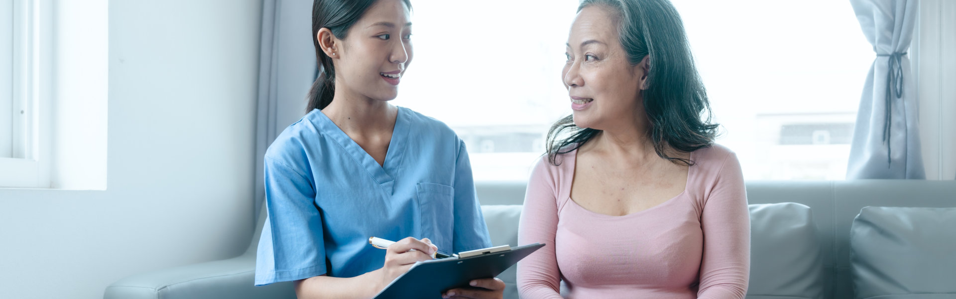 caregiver holding a clipboard talking to the senior woman