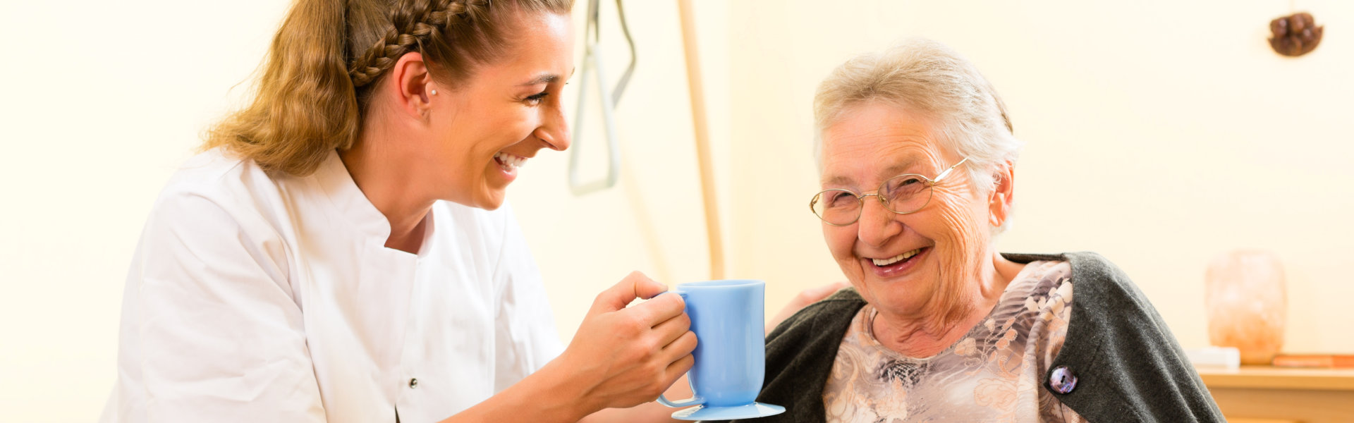 caregiver holding a cup of water for the senior woman